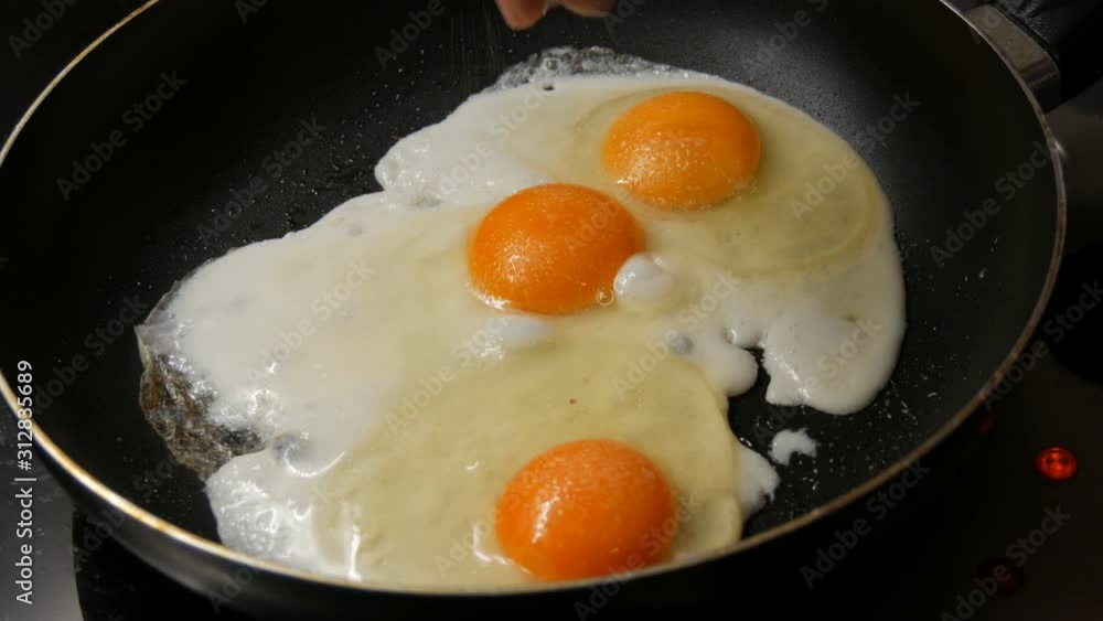 Close-up view of fried eggs in a pan sprinkled with salt Close-up view of fried eggs in a pan sprinkled with salt