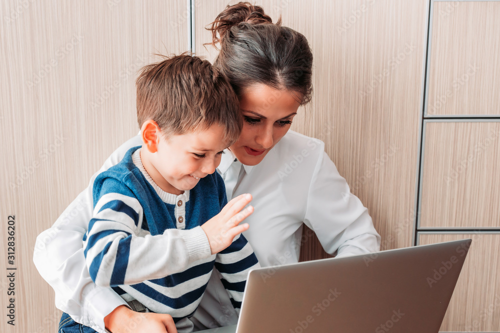 Mom and her son, sitting on the floor looking at laptop and waving. Video call Mom and her son, sitting on the floor looking at laptop and waving. Video call