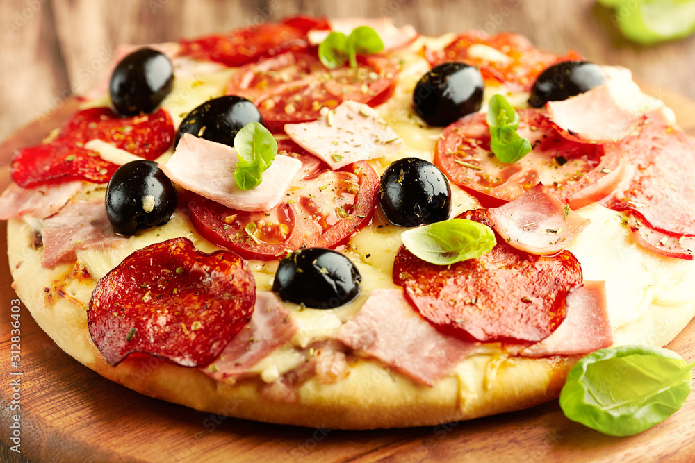 Pizza with ham, salami, champignon mushrooms, cherry tomatoes, black olives and fresh basil.