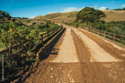 Canvastavla Dirt road on rural lowlands with hills and bridge