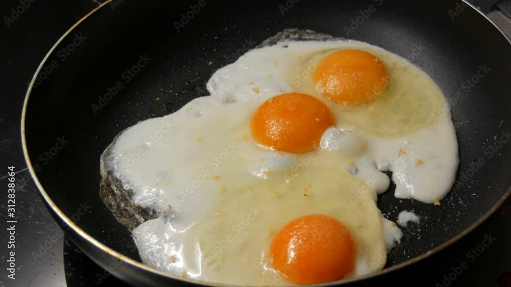 Close-up view of fried eggs in a pan sprinkled with spices Close-up view of fried eggs in a pan sprinkled with spices