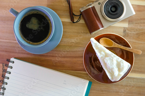 notebook, camera, coffee, coconut cake on wooden background photo