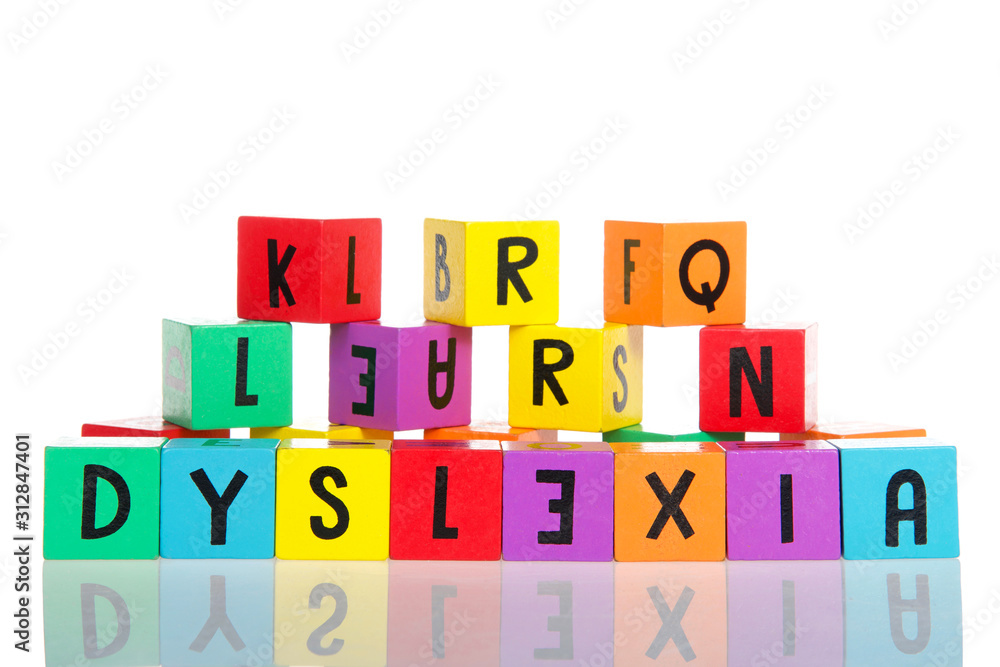 Bright colorful wooden toy blocks stacked on a reflective surface spelling dyslexia. Learning challenges disabilities. E is backwards. Isolated on white background. Bright colorful wooden toy blocks stacked on a reflective surface spelling dyslexia. Learning challenges disabilities. E is backwards. Isolated on white background.