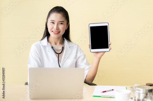 Asian woman doctor showing an empty white screen tablet, concept of maketing and commucication in medical service and hospital. photo