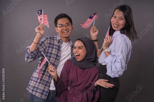Happy multi racial Malaysian people holding Malaysia Flag.Independence day and patriotic concept.Studio shot.