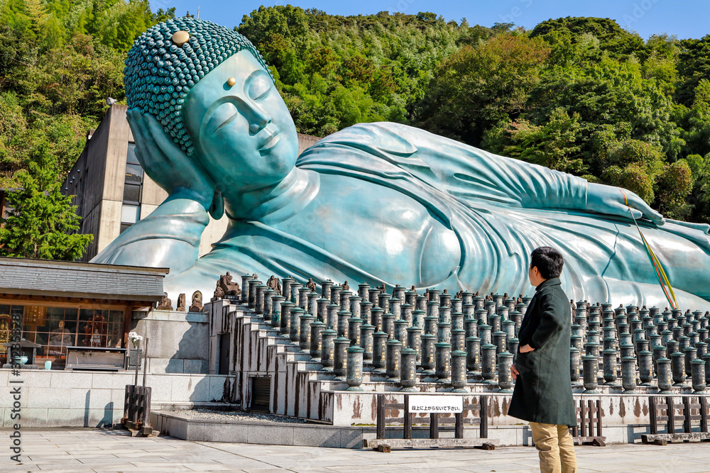 Lovely man in front of Big Buddha at Nanzo-in Temple, Fukuoka, Japan. Nanzoin is a Shingon sect Buddhist temple in Sasaguri, Fukuoka Prefecture, Japan.