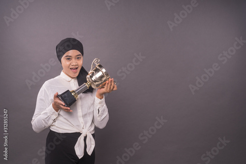 Happy young female intrepreneur or business woman holding his gold trophy and celebrating her victory.Studio shot.