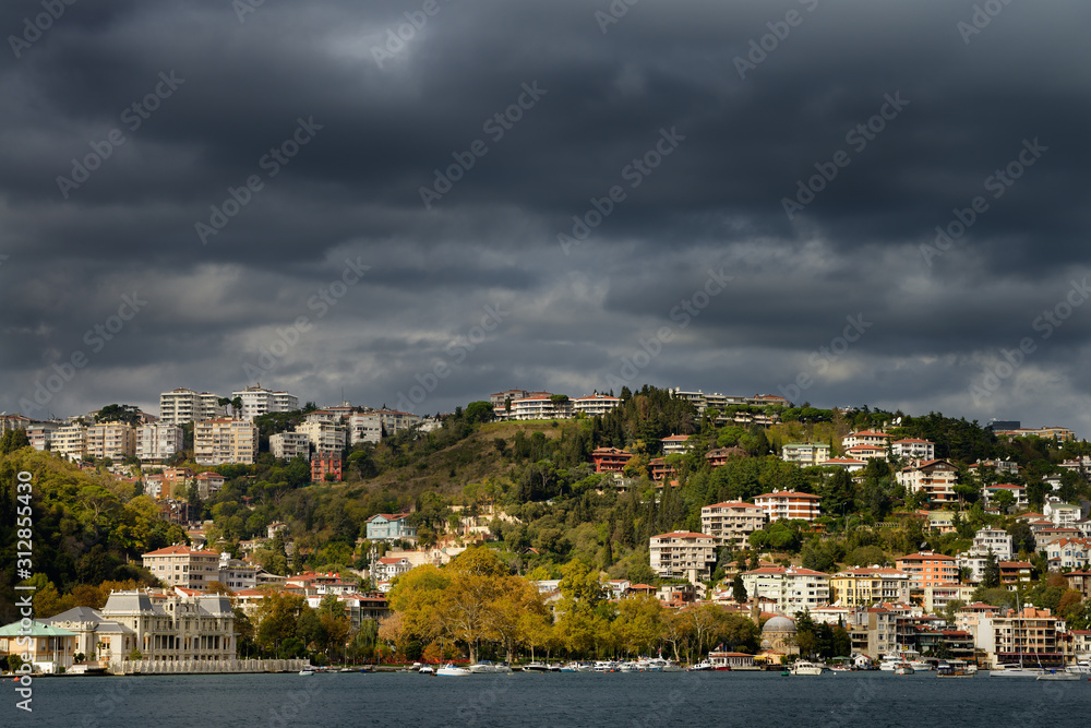 Bebek harbour Istanbul with storm clouds and sun over apartments on hill and Egyptian Consulate