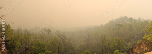 panorama of the sandy cliffs and valleys and forest stretching out from Pai canyon, a Northern Thailand tourist destination, covered in smoke