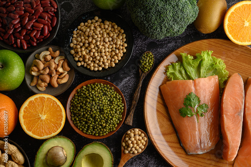 Legumes, fruit and salmon pieces on a wooden plate.