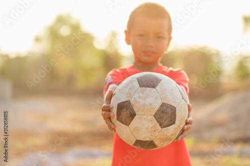 Young Asian boy playing old and dirty classic soccer ball in the morning © SKT Studio