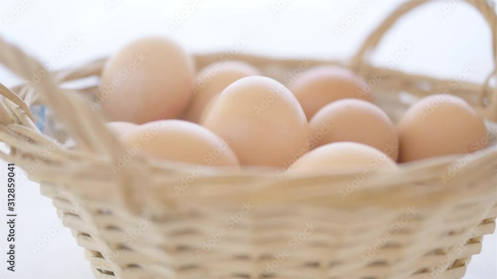 egg is being put by male hand into basket full of blurred eggs on white background soft light close up egg is being put by male hand into basket full of blurred eggs on white background soft light close up