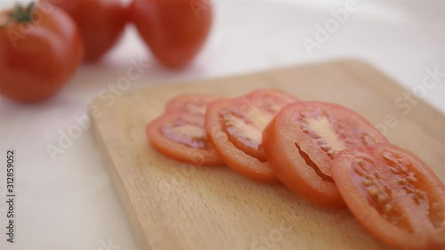 red tomatoes served on a wooden chopping board close up macro on white table background being put by male hand