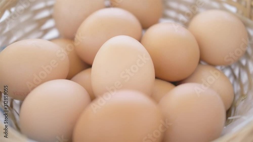 egg is being put by male hand from basket full of blurred eggs on white background soft light close up