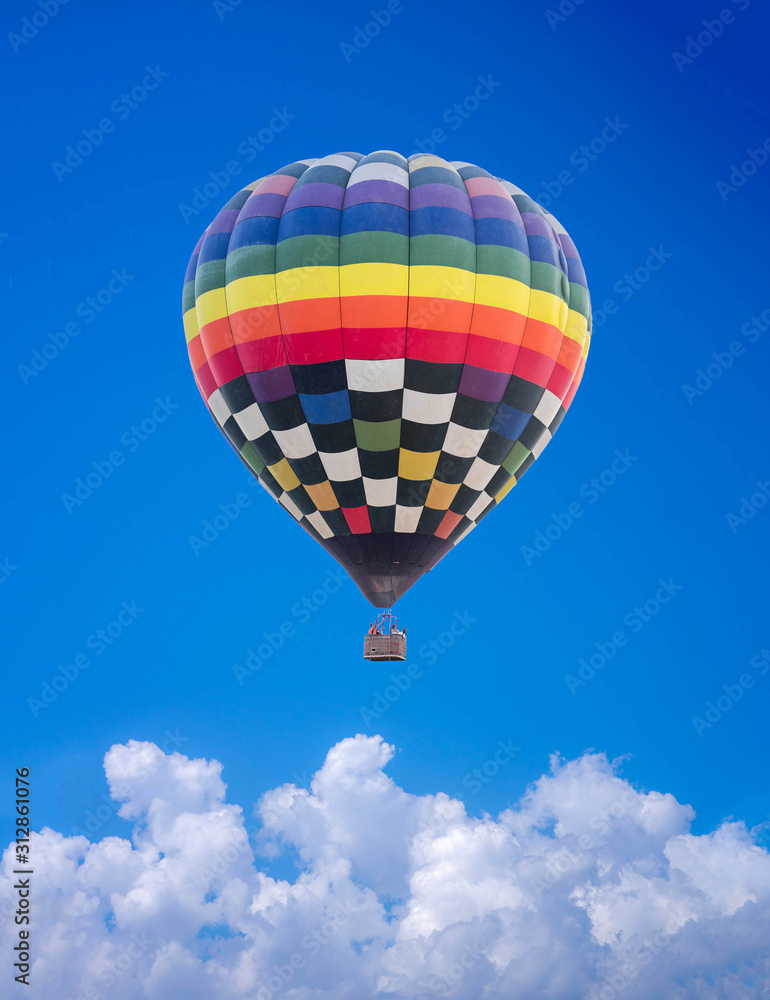 Naklejka premium Aerial view of a multicolored hot air balloon flying on blue sky.