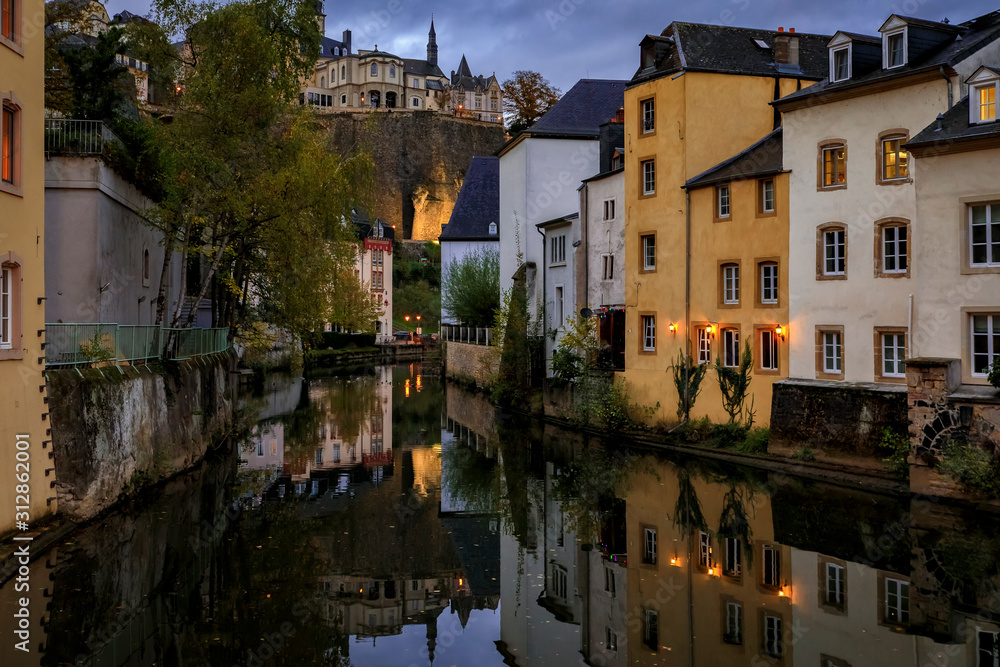 Pastel houses reflecting in Alzette river in Luxembourg old town, UNESCO World Heritage Site and the city wall at sunset