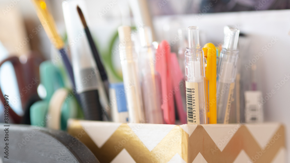 Closeup on a variety of back to school stationary supplies with colorful pens stacked into pen holder Closeup on a variety of back to school stationary supplies with colorful pens stacked into pen holder