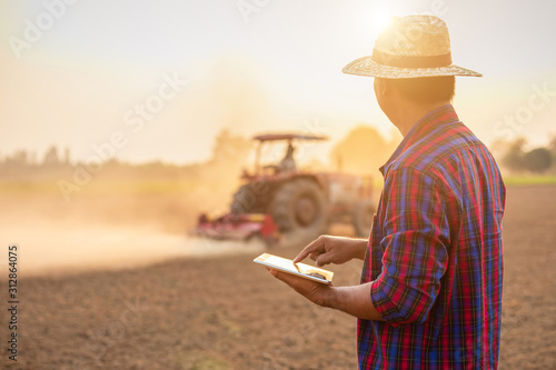 Asian young farmer working and holding tablet in the empty land. Prepare the soil and planning to planting concept photo