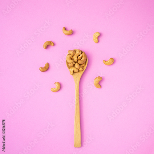 Top view fried cashew nut with salt on pink background. Copy space for text or design photo