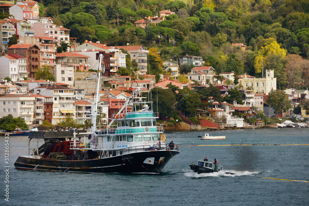 Fishermen seine fishing on the Bosphorus Strait with houses on hill at Yeni Mahalle Sariyer Turkey