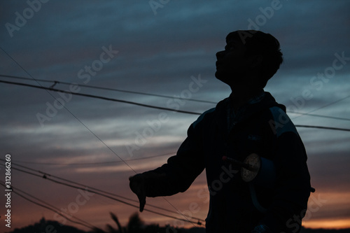 Silhouette of a little kid flying kite during sunset