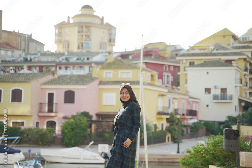Asean young hijab girl againts colorful Town houses and buildings in the town center of Valencia around port Saplaya