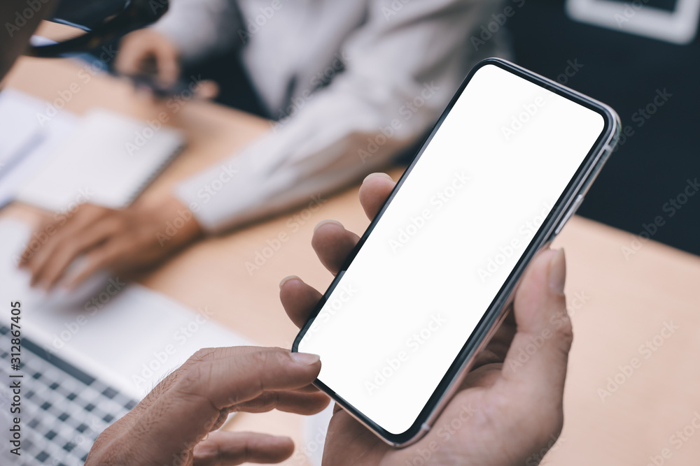 Mockup image blank white screen cell phone.man hand holding texting using mobile on desk at office.background empty space for advertise text.people contact marketing business,technology Mockup image blank white screen cell phone.man hand holding texting using mobile on desk at office.background empty space for advertise text.people contact marketing business,technology