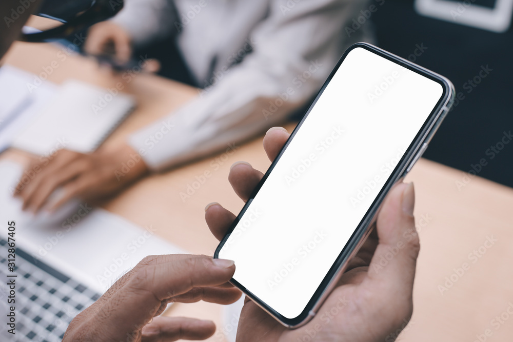 Mockup image blank white screen cell phone.man hand holding texting using mobile on desk at office.background empty space for advertise text.people contact marketing business,technology 