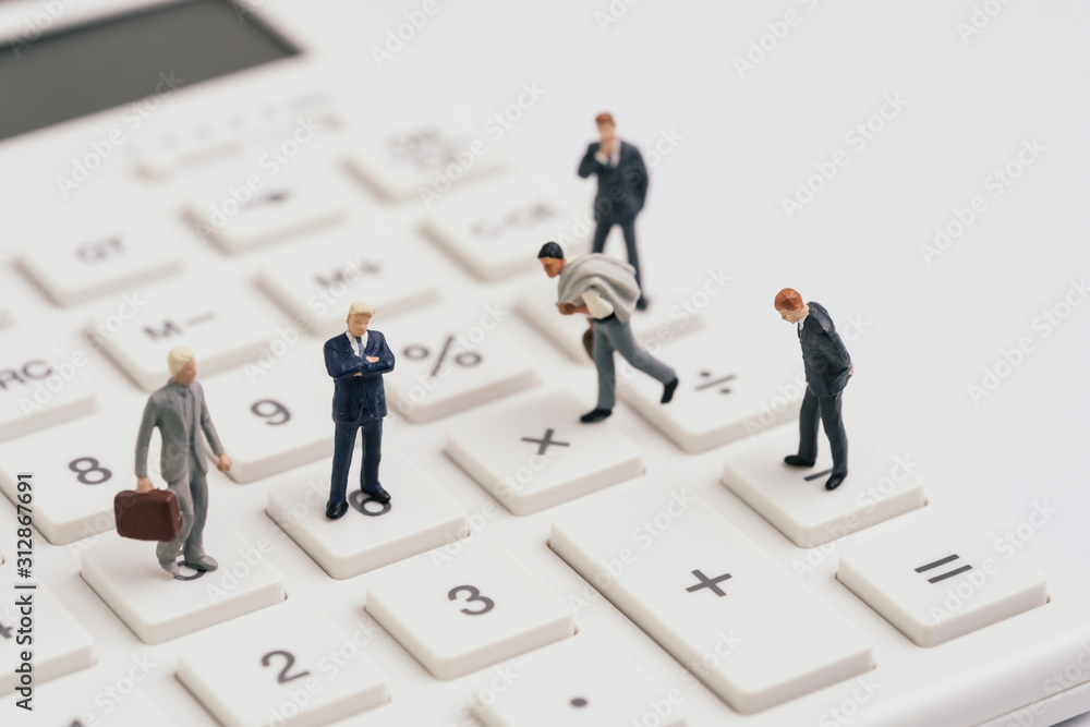 Miniature people businessmen figure standing on white calculator on white background using as teamwork ,business performance success, profit and loss in accounting or company management concept Miniature people businessmen figure standing on white calculator on white background using as teamwork ,business performance success, profit and loss in accounting or company management concept