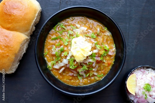 Indian Mumbai Street style Pav Bhaji, garnished with raw onions, coriander and Butter. Spicy thick curry made of out mixed vegetables, served with Bread