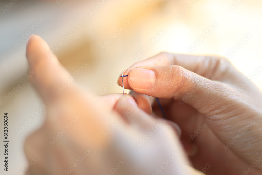 Closeup finger thread into the needle hole (Success began from a small thing) Closeup finger thread into the needle hole (Success began from a small thing)