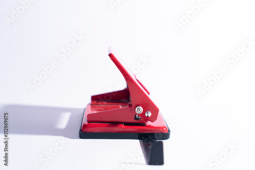 Red hole punch on a white background. Side view of a hole punch.