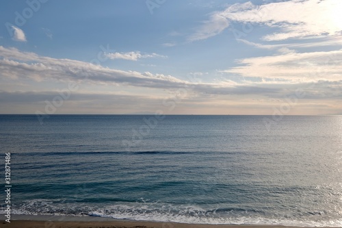 blue sea horizon under sunny clouds sky. waves against beach