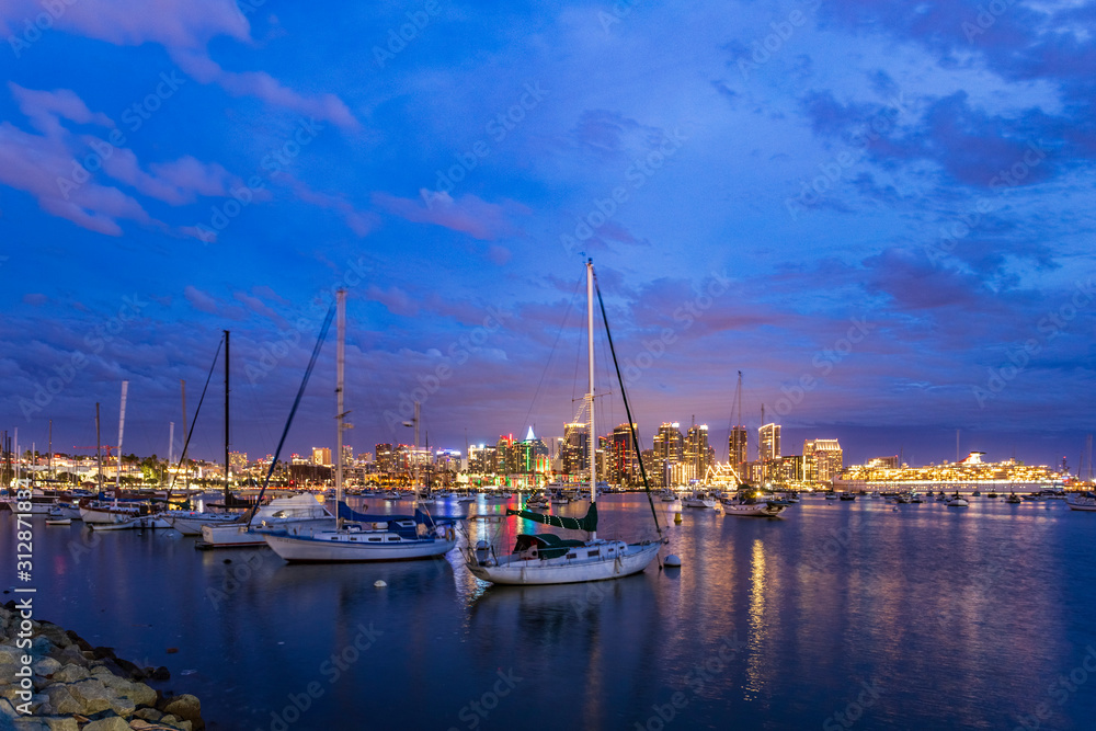 Sailboats in the harbor with San Diego city skyline in the background at night