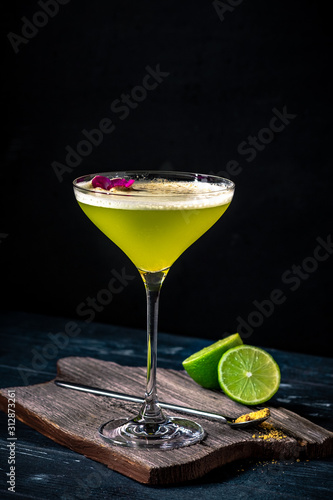 Classic alcoholic cocktail Daiquiri with lime and kiwi in a glass on a black background. Tropical vermouth with green fruit.