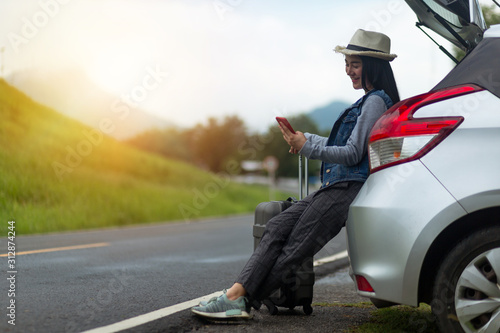 Beautiful stylish young girl travels by car, with a hat and with a card in her hands, summer travel, freedom.