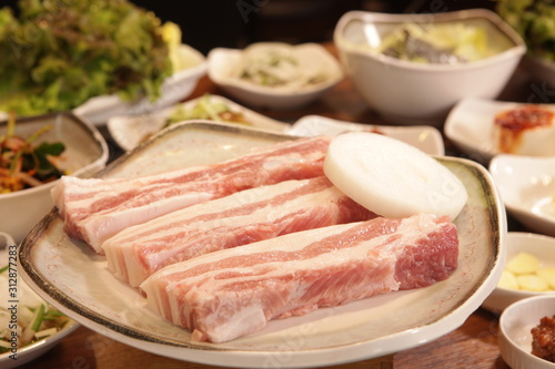 돼지고기가 양파와 함께 접시에 놓여있다(The pork belly is placed on a plate with sesame leaves and onions)