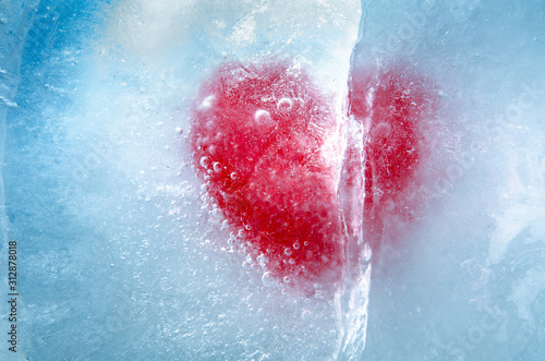 Red heart frozen in ice with a big crack, a symbol of love or betrayal or separation