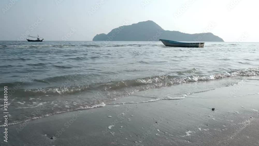 Beautiful thailand coastline on a sandy beach, waves was crashing onto the shoreline, on a bright sunny day, beauty nature sea background. wide view of a cliff and boat in the distance Beautiful thailand coastline on a sandy beach, waves was crashing onto the shoreline, on a bright sunny day, beauty nature sea background. wide view of a cliff and boat in the distance
