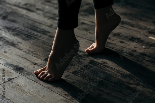 Female feet walking on warm heated floor close up view, barefoot girl legs going on hardwood living room wooden flooring at modern home house, domestic underfloor heating concept, close up rear view