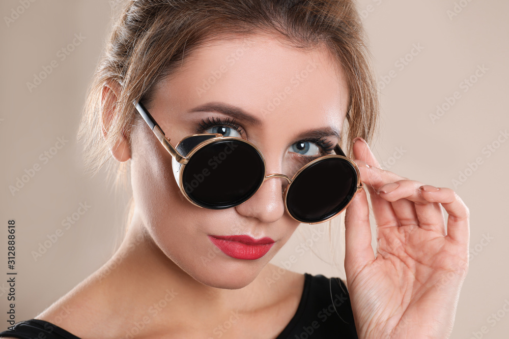 Young woman wearing stylish sunglasses on beige background Young woman wearing stylish sunglasses on beige background