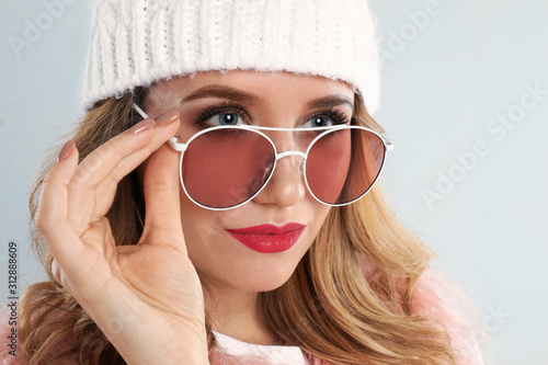 Young woman wearing stylish sunglasses on light grey background