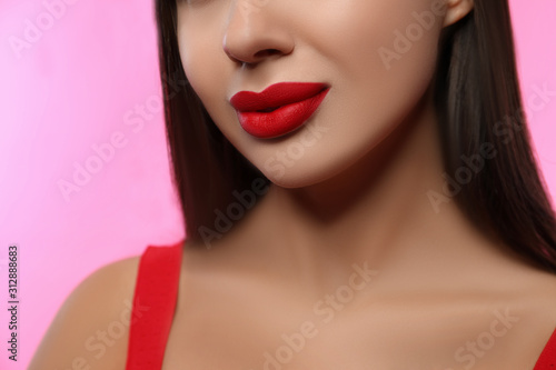 Woman with red lipstick on pink background, closeup