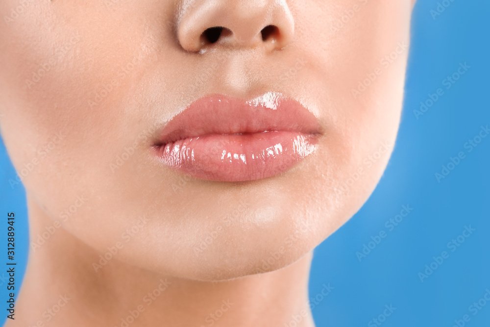 Obraz premium Young woman with beautiful full lips on light blue background, closeup