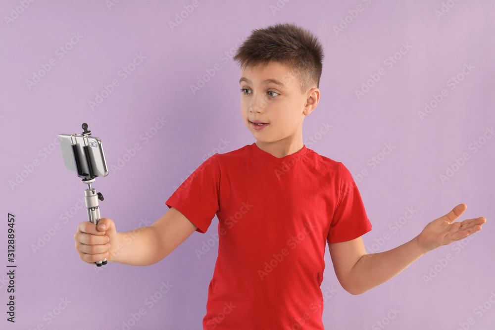Cute little blogger recording video on violet background Cute little blogger recording video on violet background