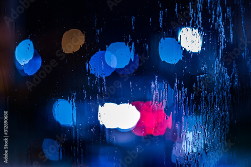 an abstract background of red and blue police lights bokeh trough wet glass at night close-up with selective focus photo