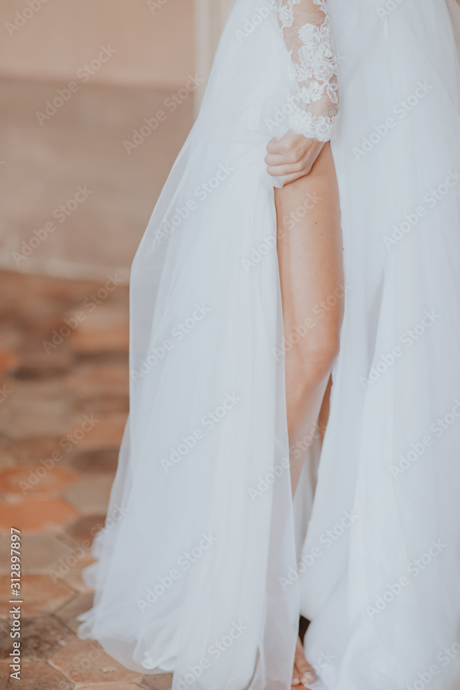 La mariée tenant délicatement le voile de sa robe La mariée tenant délicatement le voile de sa robe