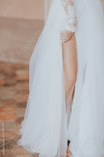 La mariée tenant délicatement le voile de sa robe