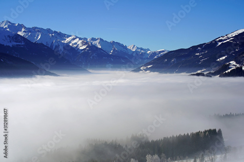 beautiful view to the snow capped mountains in austria with a misty valley