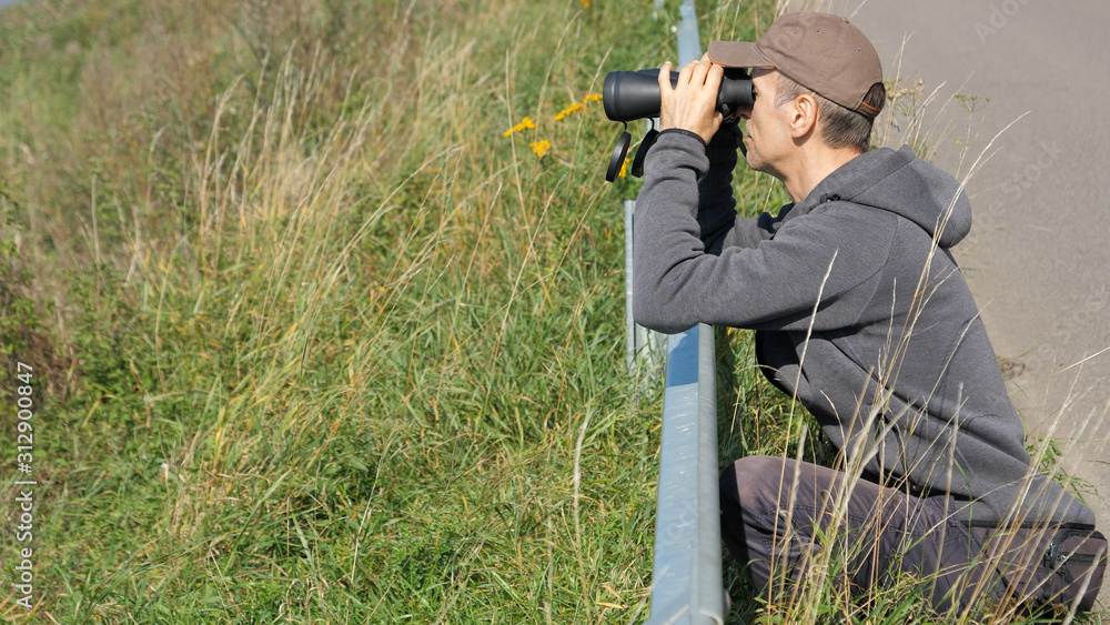 Bird watching. Man is looking through the binoculars